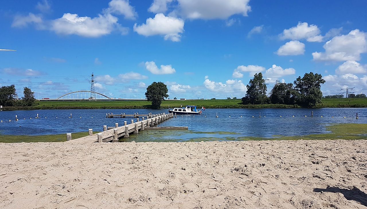 Het strand van De Kogeloven met de steiger en een aangemeerde boot op het Brielse Meer